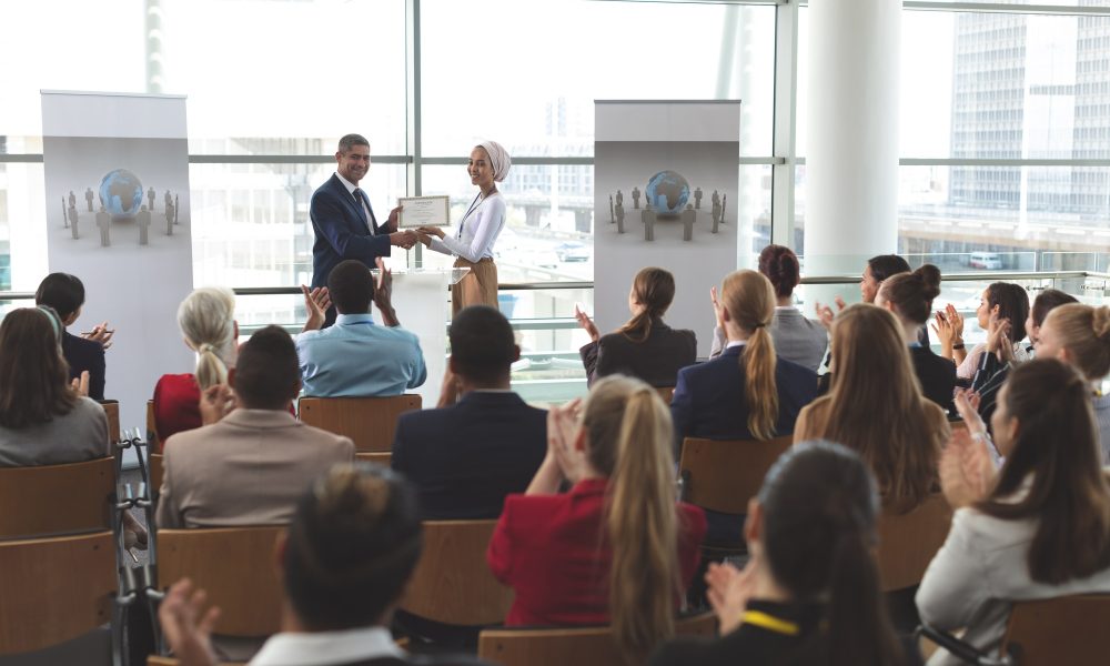 businesswoman-receiving-award-from-businessman-at-business-seminar-in-office-building.jpg